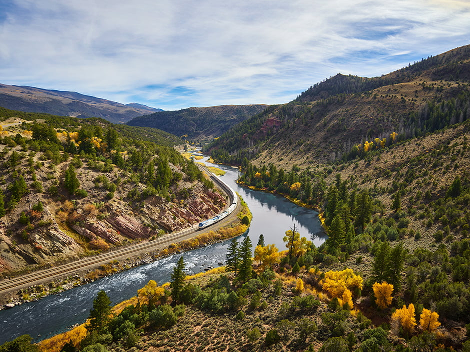 Amtrak train traveling by a river