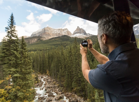Scenery of Rocky mountaineer train man taking picture of scenery on rocky mountaineer train
