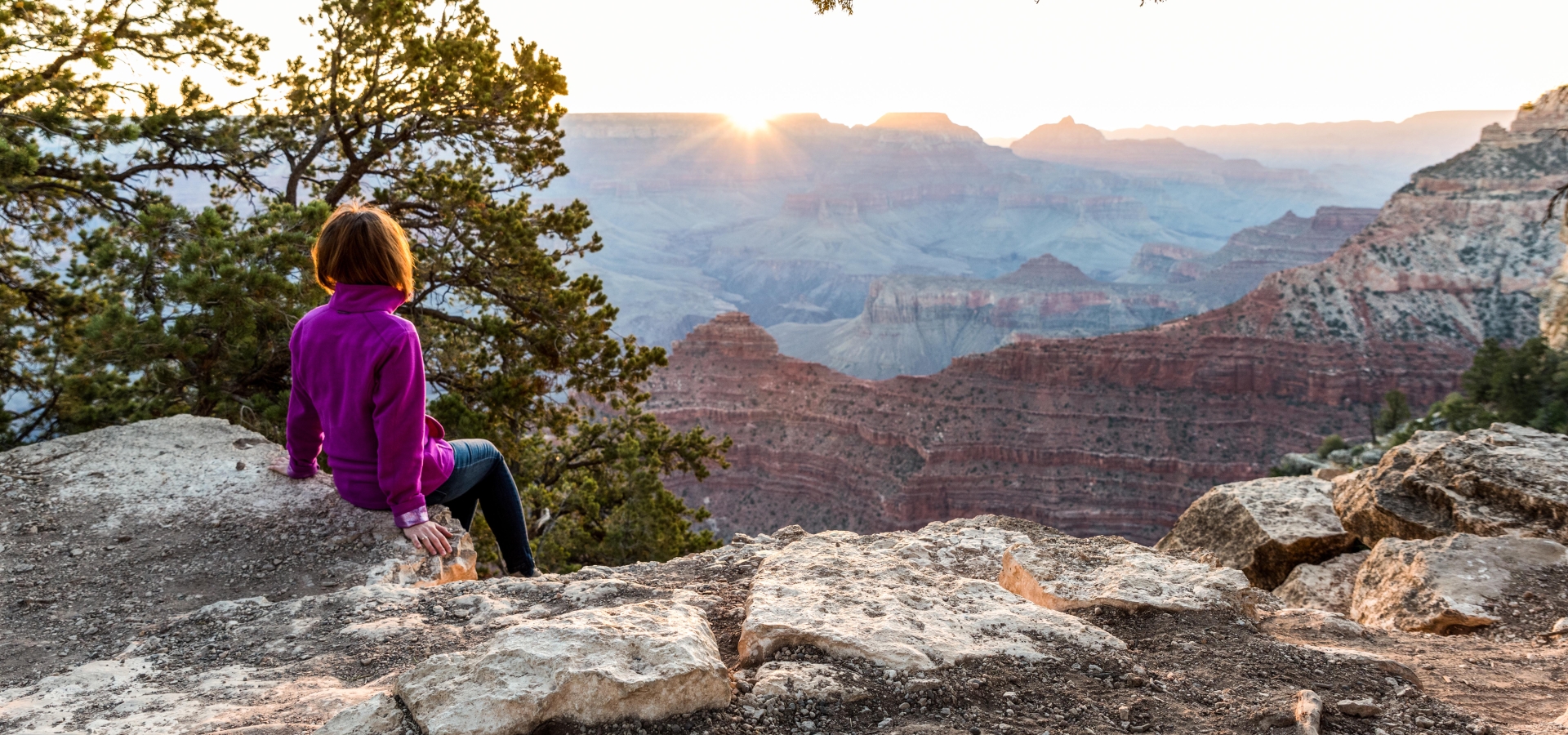 Tourist Is Seating On The Edge of Cliff and Watching of Sunrise at Grand Canyon from Mather Point